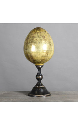 Grande ovo amarelo em vidro soprado em uma base de madeira esculpida preta