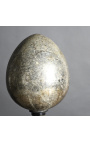 Duże srebrne jajko w dmuchanym szkle na czarnej rzeźbionej drewnianej podstawie